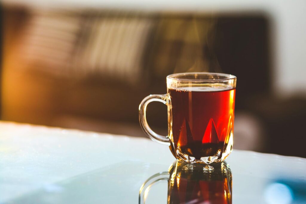 Enjoy a warm, steaming glass of tea in a cozy sunlit room, perfect for relaxation.